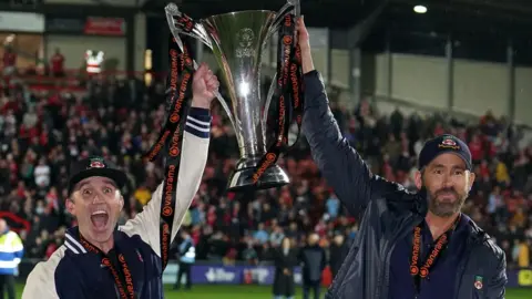 PA Media Wrexham co-owners Rob McElhenney and Ryan Reynolds celebrate with the Vanarama National League trophy