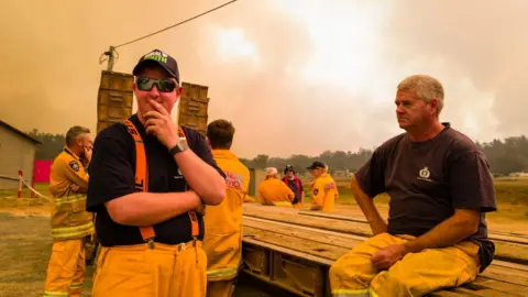 Getty Images Firefighters take a break from battling a bushfire near the town of Miena in Tasmania