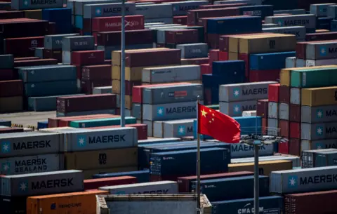 Getty Images A Chinese flag is seen in front of containers at the Yangshan Deep-Water Port, an automated cargo wharf, in Shanghai on April 9, 2018.