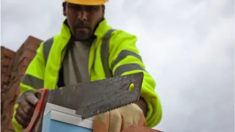 Construction Photography/Avalon A worker cuts insulation