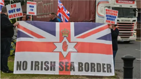 Getty Images Loyalists protesting against the Northern Ireland Protocol with a banner reading 'No Irish Sea Border'