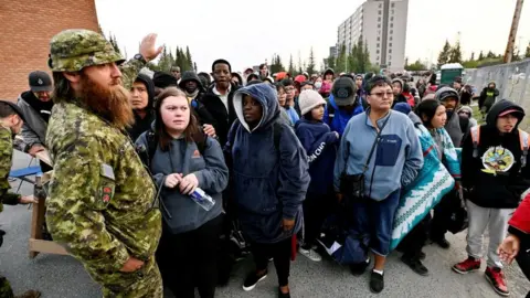 Reuters People line up outside of a local school to register to be evacuated, as wildfires threatened the Northwest Territories town of Yellowknife, Canada, August 17, 2023. REUTERS/Jennifer Gauthier TPX IMAGES OF THE DAY