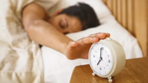 Getty Images A woman hits an alarm clock