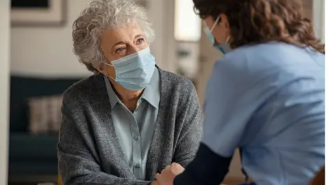 Getty Images Woman in a mask with a health professional