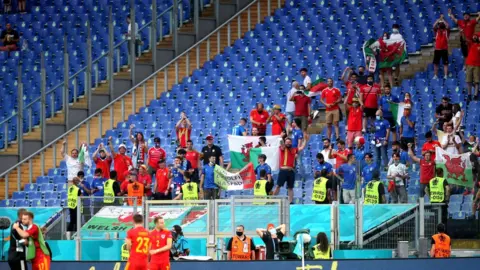 PA Media Wales fans applaud their team after the match against Italy in Rome