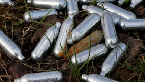 PA Media Canisters of nitrous oxide, or laughing gas, discarded by the side of a road