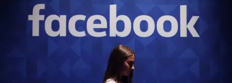 PA File photo dated 03/11/15 of a woman using her phone under a Facebook logo