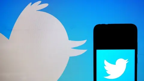 Getty Images Twitter logo on phone on background of Twitter logo