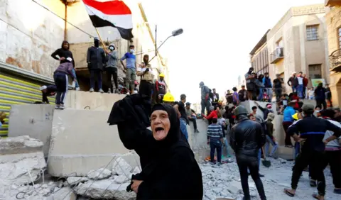 Reuters A woman shouts in front of anti-government protesters in Baghdad, Iraq (21 November 2019)