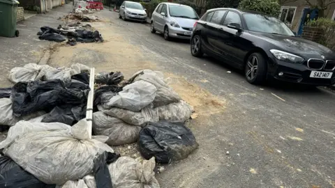 Bags of rubble shown at the side of the road