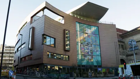 BBC A picture of the Bristol Beacon building from the front. It is low light and there is Black Lives Matter artwork on the front windows.