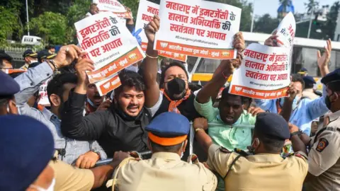 Getty Images Activists and supporters of Bharatiya Janata Party (BJP) hold placards as they scuffle with police during a protest.