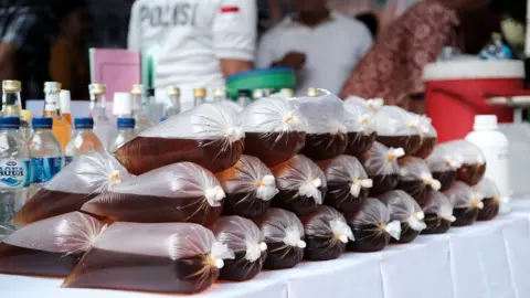 Getty/BAGUS SARAGIH Seized illegal alcohol on display at a police press conference in Jakarta