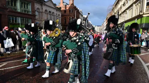 Pacemaker Press The picture shows a number of men playing bagpipes through Belfast city centre. They are wearing beefeater type hats and green tartan 