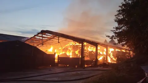 A barn containing hay bales on fire
