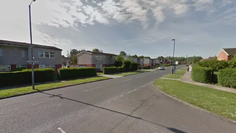 A road with houses on either side with a junction onto another road. 