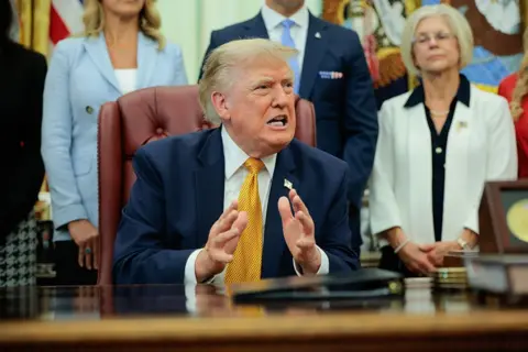 US President Donald Trump speaks to the media after signing an executive order establishing the President's Military Spouse Commission in the Oval Office at the White House on August 03, 2026 in Washington, DC. 
