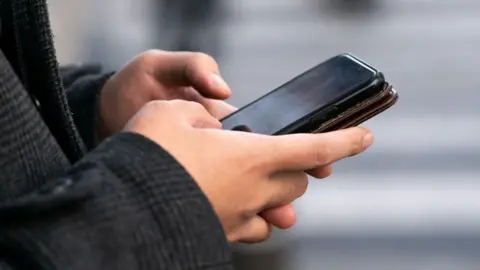Close-up shot of a man's hands as he types on his smartphone.