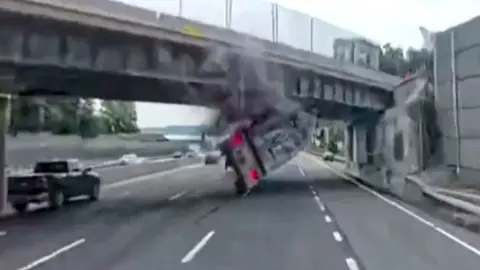 A tractor trailer is flipped over after hitting the overpass.