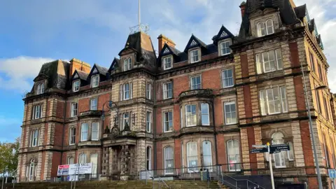 A large, brick-built building, with a number of bay windows and ornate features.