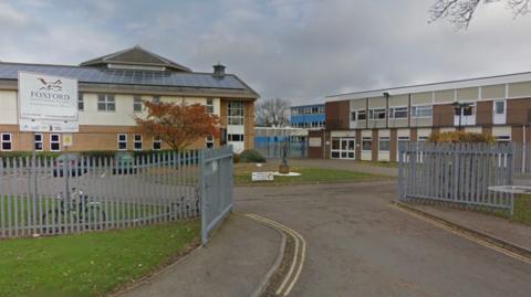 Street view of Foxford School & Community Arts College. The brick two-storey building is surrounded by a grey metal fence