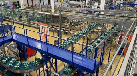 Crates of Perrier bottles travel around a factory floor on conveyor belts