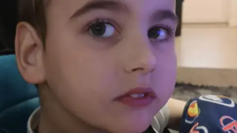 The close family of Jacob, 10, with brown eyes and brown hair is sitting in a precious chair.  