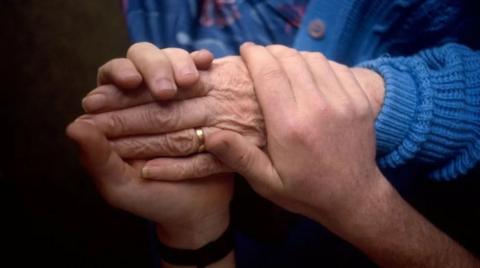 Carer holding the hand of an older person