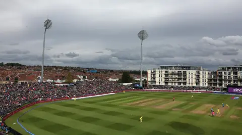 Getty Images A wide shot of the county cricket ground in Bristol as England played Australia in a one-day international. Australia are fielding in their yellow kit and the full grandstands and housing estates are visible in the background, along with the stadium's large floodlights