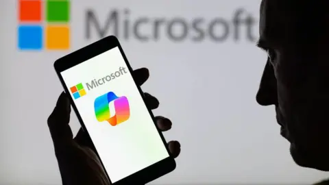 A man holds a phone with the Microsoft Copilot logo on the screen