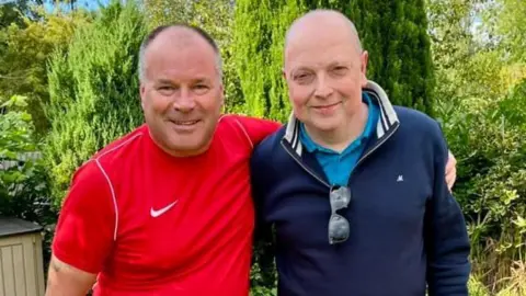 Two men, one in a red t-shirt and the other in navy