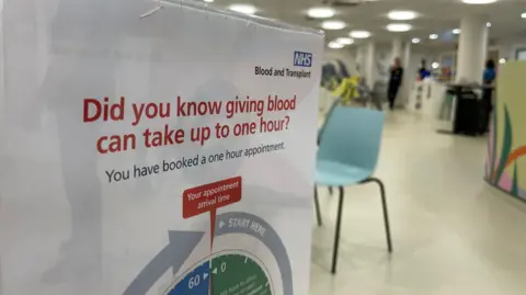 Mark Norman BBC A sign in the blood donation centre in Brighton highlighting the fact it can take one hour to donate blood. 