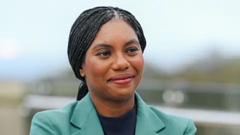 PA Media Kemi Badenoch's head and shoulders. She has braided hair, centre-parted, and is wearing a green jacket.