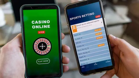 Getty images are a close-up shot sitting inside the house of an unfamiliar man and woman, they are placing smart phones in their hand and they are using them to gamble in online casino and sports conditions online.