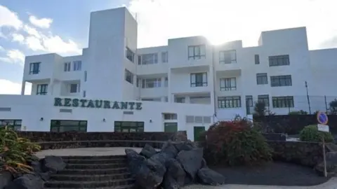 The outside of the Galeon Playa apartments with a sign for a restaurant seen in the foreground.