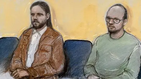 Court artist drawing of Jamie Varley (left) sitting in the dock at Preston Crown Court with long dark hair and a beard wearing a white shirt and brown jacket with co-accused John McGowan-Fazakerley who is nearly bald with a short dark beard and glasses and a green sweatshirt