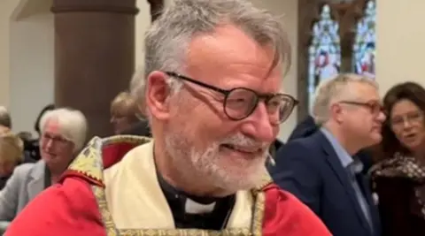 Nigel Godfrey in ceremonial robes of red and cream.