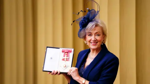 PA Media Dame Andrea Leadsom, wearing a blue blazer and fascinator hat, after being made a Dame Commander of the British Empire for services to politics by the Prince of Wales during an investiture ceremony at Buckingham Palace, London