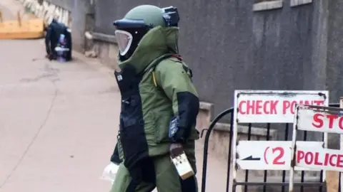 Reuters A bomb disposal expert dressed in his protective suit lays a cable as he prepares a controlled detonation of an explosive device outside a Pentecostal church, Lubaga Miracle Centre, in the Lubaga suburb of south Kampala, Uganda September 3, 2023.