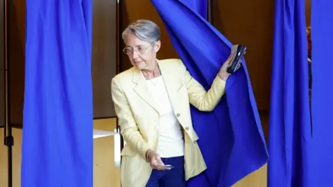 Reuters French Prime Minister Elisabeth Borne, candidate under the presidential majority "Ensemble", leaves a polling booth in the first round of French parliamentary elections, at a polling station in Vire-Normandie