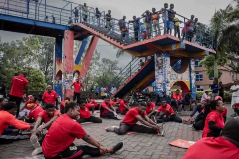 AFP A group of people participate in sports exercises while others look on at a public square in Goma on November 20, 2022