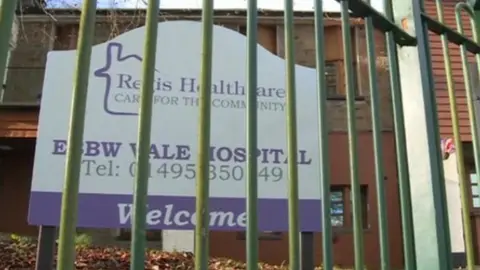 BBC A picture of Regis Healthcare's sign behind a barred fence