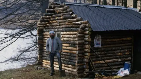 Ken Smith Ken with his log cabin soon after it was built in the early 1980s