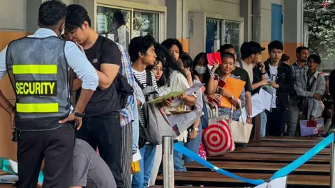 Getty Images People queue to get visas in front of the embassy of Thailand in Yangon on February 16, 2024, after Myanmar's military government said it would impose military service. 