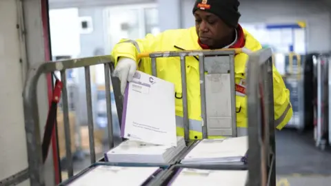 PA Media Postman Adrian Alleyne loads a truck with 2011 Census questionnaires at the Mount Pleasant Mail Centre in London ahead of one of the biggest single mailouts the Royal Mail has handled as Census questionnaires will begin dropping through people's letterboxes from tomorrow.