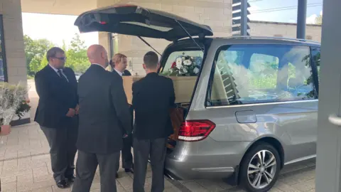 BBC/Amy Walker Pallbearers with the coffin at Wealden Crematorium