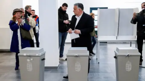 Reuters Hungarian Prime Minister Viktor Orban holds his ballot paper, at a polling station during the Hungarian parliamentary election, in Budapest, Hungary, April 3, 2022