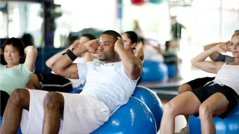 Getty Images A group of adults doing abdominal crunches in a gym