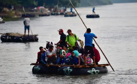 AFP/Getty Images Several makeshift rafts carry migrants across the river