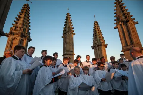 Getty Images The Magdalen College Choir sing the Hymnus Eucharisticus from the top of the Great Tower, Magdalen College, Oxford